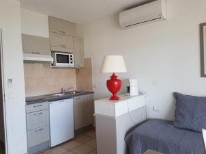 uma pequena cozinha com um candeeiro vermelho ao lado de uma cama em Appartement Saint-Raphaël, 2 pièces, 4 personnes - FR-1-466A-2 em Saint-Raphaël