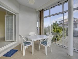 ein weißer Tisch und Stühle in einem Raum mit Fenstern in der Unterkunft Villa 2 chambres proche plage, jardin, véranda, clim, wifi à Biscarrosse - FR-1-521-19 in Biscarrosse-Plage + 3 Fotos