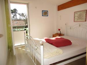 a bedroom with a white bed with a red pillow at Maison T3 à Biscarrosse Lac - 4/6 pers - Jardin, terrasse, proche lac et pistes cyclables - FR-1-521-116 in Biscarrosse