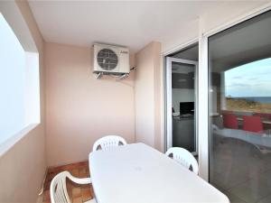 Una mesa blanca y sillas en una habitación con balcón. en Studio Banyuls-sur-Mer, 1 pièce, 4 personnes - FR-1-309-210, en Banyuls-sur-Mer