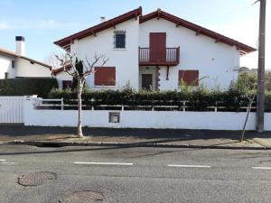 ein weißes Haus mit roten Rollläden auf einer Straße in der Unterkunft Maison 3* à Hendaye, proche plage et commerces, jardin privé, parfait pour familles et amis - FR-1-239-492 in Hendaye