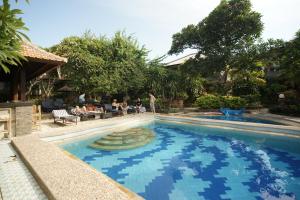una piscina in un resort con persone sedute di Ramayana Hotel a Sanur
