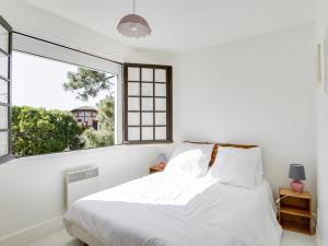 a bedroom with a white bed and a large window at Maison Biscarrosse Plage, 4 pièces, 8 personnes - FR-1-521-94 in Biscarrosse-Plage