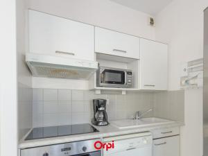a kitchen with white cabinets and a microwave at Appartement T2 à 50m de la plage avec piscine, tennis et balcon - Châtelaillon-Plage - FR-1-535-4 in Châtelaillon-Plage