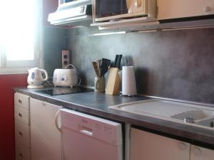 a kitchen with a counter top with a stove and a sink at Appartement 2 pièces en front de mer avec balcon, à 70m de la plage de Cabourg - FR-1-487-287 in Cabourg