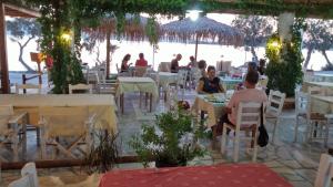 a group of people sitting at tables in a restaurant at Sunset in Agios Prokopios