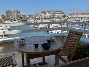 un tavolo in legno su un balcone con porto turistico di Appartement Dives-sur-Mer, 4 pièces, 6 personnes - FR-1-487-314 a Dives-sur-Mer