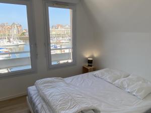 a bedroom with a bed and two windows with boats at Bel Appartement Duplex 4 pièces avec Vue sur Port et Terrasse - FR-1-487-314 in Dives-sur-Mer
