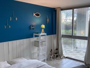 ein Schlafzimmer mit einer blauen Wand, einem Bett und einem Fenster in der Unterkunft Appartement Cabourg, 4 pièces, 6 personnes - FR-1-487-321 in Cabourg