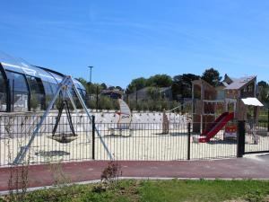 un parque infantil con toboganes y columpios frente a un autobús en Mobil-Home Jullouville, 4 pièces, 6 personnes - FR-1-361A-16, en Jullouville-les-Pins