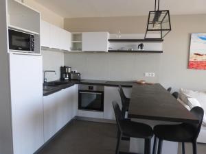a kitchen with white cabinets and a black table and chairs at Appartement luxe 2 chambres, balcon, accès plage, piscine, animaux admis, parking - FR-1-194-236 in La Tranche-sur-Mer +13 photos