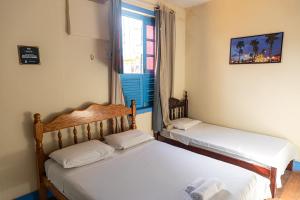 2 camas en una habitación pequeña con ventana en Pousada Aruans Casarão, en Bragança
