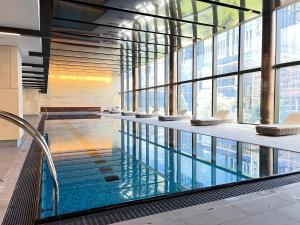 a large swimming pool in a building with windows at Rest SkyHigh Melbourne Qtr Collection in Melbourne