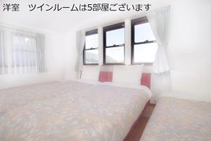 1 dormitorio con 2 camas y ventana en アルヴィラ近江舞子, en Minami-komatsu