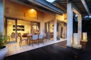 a porch of a house with chairs and a table at Villa Ananda by Optimum Bali Villas in Seminyak