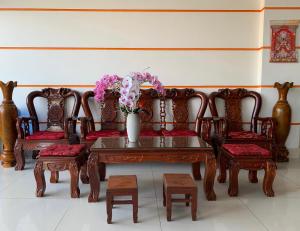 a group of chairs and a table with a vase of flowers at Ngoc May Guesthouse in Chau Doc
