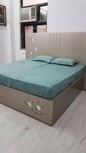 Bett mit einem Holzrahmen und einer grünen Matratze in der Unterkunft Kailash Haveli in Bikaner