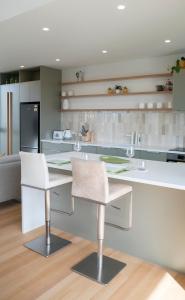 a kitchen with two white chairs and a counter at Coastal Living in Comfort in Raglan