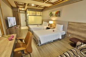 um quarto de hotel com duas camas e uma mesa e cadeiras em Lotus Saigon Hotel em Ho Chi Minh