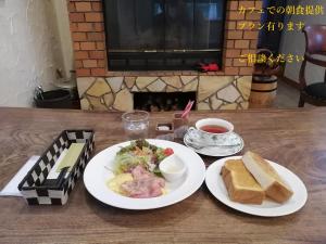 una mesa con dos platos blancos de comida y pan en アルヴィラ近江舞子 en Minami-komatsu