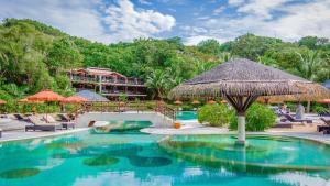 een zwembad met een rieten parasol en een resort bij Garrya Tongsai Bay Samui in Choeng Mon Beach