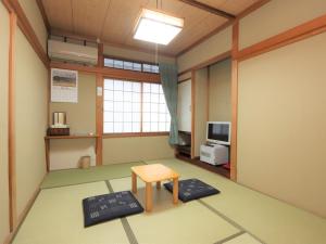 een kamer met een tafel en een tv. bij Minshuku Iwatakan in Takayama