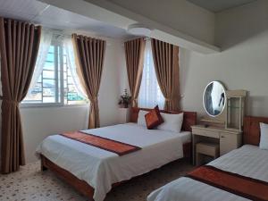 Cette chambre comprend 2 lits et un miroir. dans l'établissement Thien Phu Guesthouse Dalat, à Đà Lạt