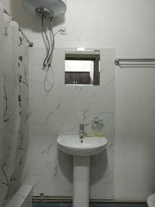 a white bathroom with a sink and a mirror at Nomad Inn in Bishkek