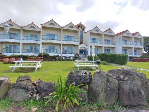 a large apartment building with two benches in the yard at Herb in Pension in Jeju