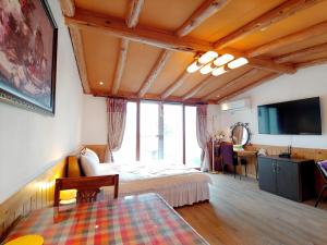 a bedroom with a bed and a desk and a tv at Herb in Pension in Jeju