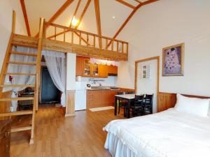 a bedroom with a loft bed and a kitchen at Herb in Pension in Jeju