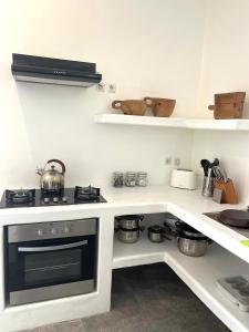 a kitchen with a stove and shelves with pots and pans at Cabana in Gili Islands