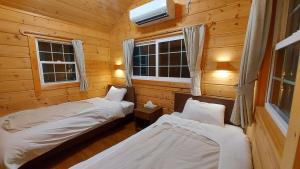 Habitación con 2 camas en una cabaña de madera en 安曇野遊人Ｃ.Ｌ.Ｊ.クラブ en Azumino