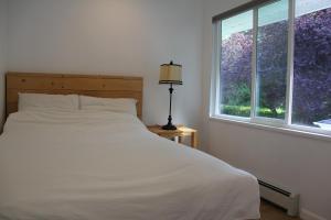 um quarto com uma cama branca e uma janela em Ocean Park B&B em Surrey