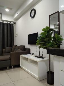 a living room with a couch and a clock on the wall at Tapeer Homestay 13CC99 @D Perdana Kota Bharu in Kota Bharu