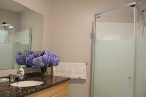 a bathroom with a sink and a vase of purple flowers at Ocean Park B&B in Surrey