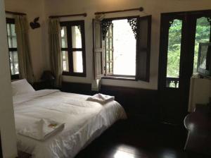 a bedroom with a white bed and windows at View Khemkhong Guesthouse in Luang Prabang