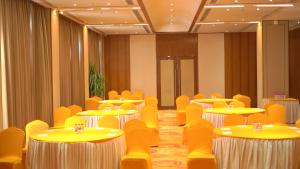 a room with tables and chairs and yellow chairs at Pride Hotel Udaipur in Udaipur