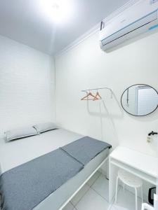 a white bedroom with a bed and a desk at Stay Hub in Timuran