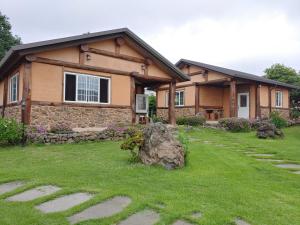 a house with a grass yard in front of it at Geumok Log Pension in Seogwipo