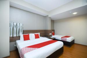 a hotel room with two beds with red pillows at Super OYO 977 Hong Kong Suites in Miri