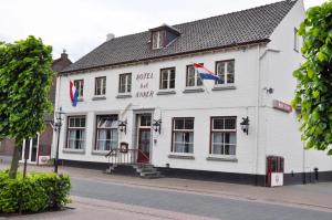 Un bâtiment blanc avec drapeaux sur une rue dans l'établissement Hotel Het Anker, à Heythuysen