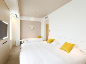 a bedroom with a large white bed with yellow pillows at Tenza Hotel at Sendai Station in Sendai