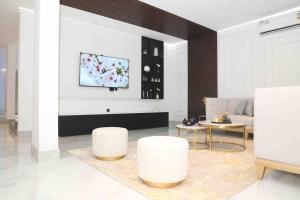 uma sala de estar com dois bancos brancos e uma televisão em Cloud Villa Salalah em Salalah