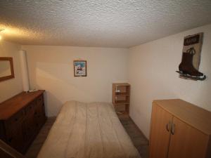 ein kleines Schlafzimmer mit einem Bett und einem Holzschrank in der Unterkunft Appartement Auris, 2 pièces, 8 personnes - FR-1-297-73 in Auris
