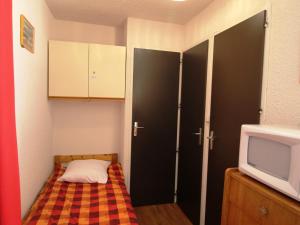 a small room with a bed and a tv at Appartement Auris, 1 pièce, 4 personnes - FR-1-297-41 in Auris