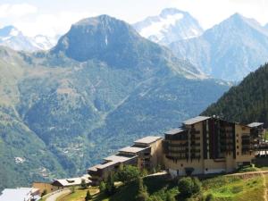 a building on a hill with mountains in the background at Studio cabine 3 couchages au pied des pistes, ascenseur, casiers à ski, parking - Auris en Oisans - FR-1-297-76 in Auris +9 photos
