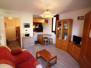 a living room with a red couch and a kitchen at Appartement Auris, 1 pièce, 4 personnes - FR-1-297-117 in Auris