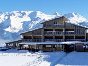 a building in the snow with mountains in the background at Appartement Auris, 1 pièce, 4 personnes - FR-1-297-68 in Auris