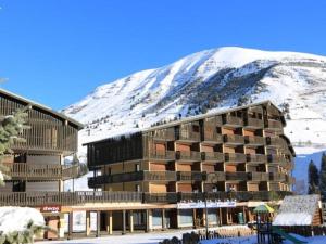 un edificio frente a una montaña nevada en Appartement lumineux 2 pièces cabine, balcon, au pied des pistes - 4 couchages - Auris en Oisans - FR-1-297-75, en Auris